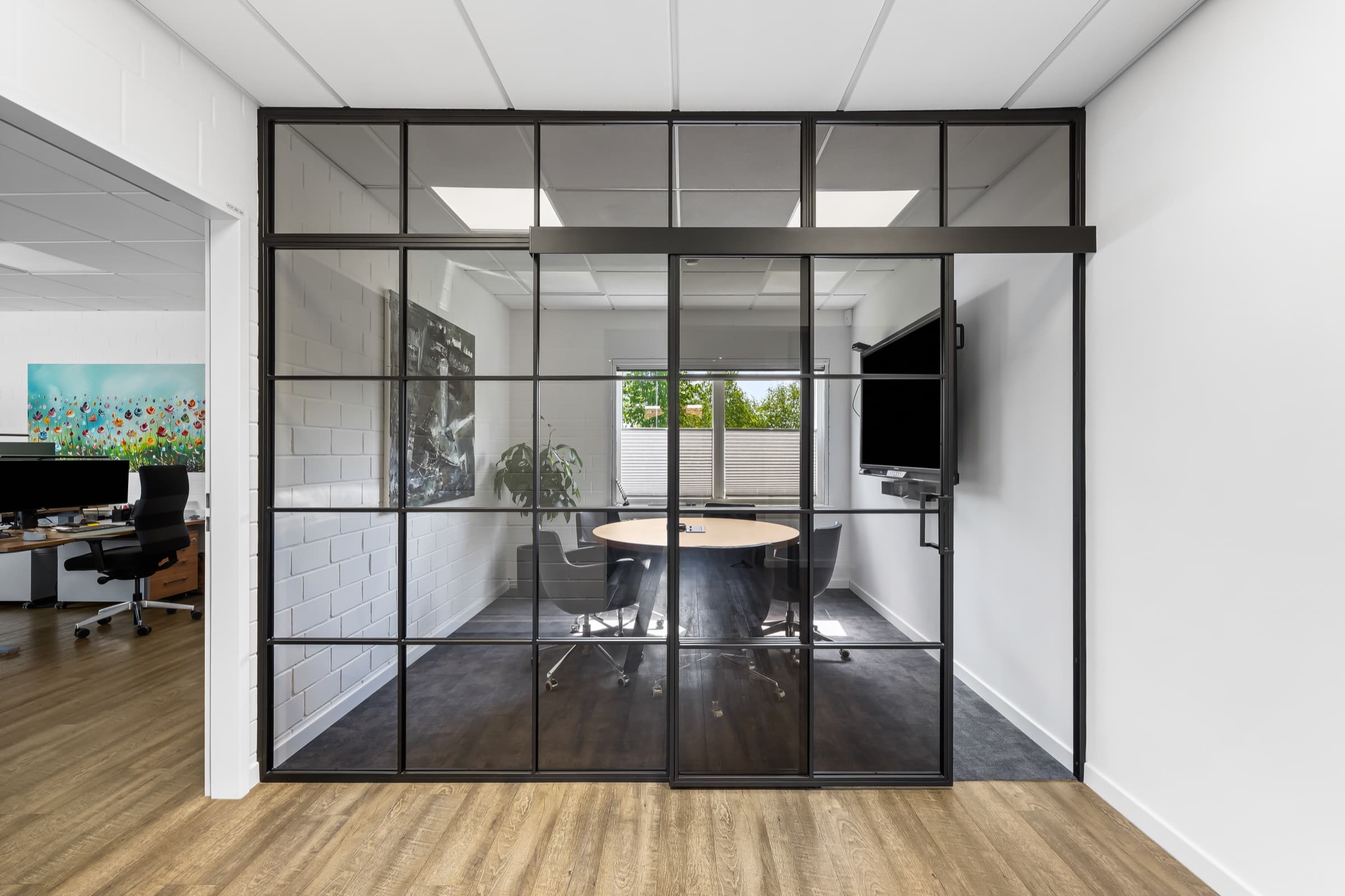 Czarna ścianka stalowo-szklana z drzwiami dwuskrzydłowymi i naświetlem przed salą spotkań