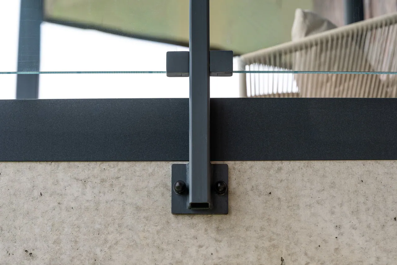 Słupek balustrady z przykręcaną stopą przy betonowej krawędzi